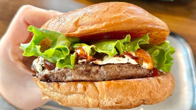 a hand holds up a burger