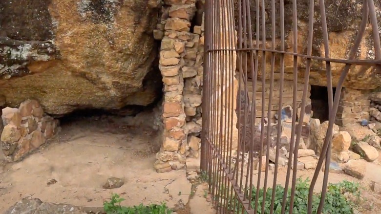 Rusty cage next to pile of rocks and animal den
