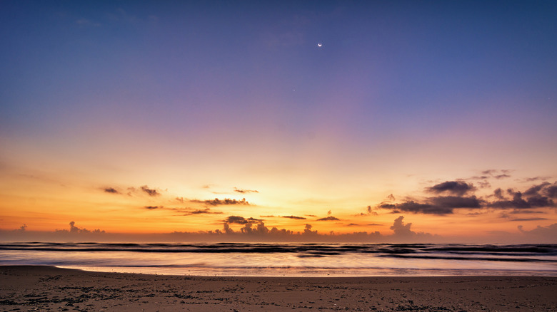 Sunset of hues from purple to orange over the sand and waves of Brazos Island State Park
