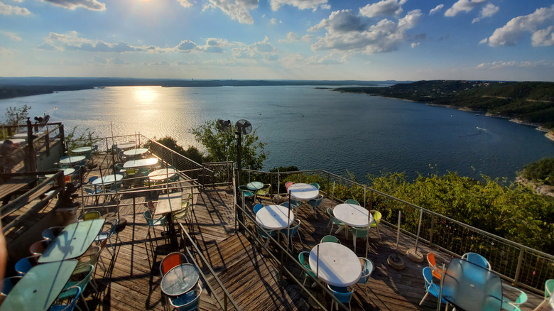 Sun-drenched balconies with tables and chairs at The Oasis on Lake Travis restaurant and bar overlooking the lake and blue sky.