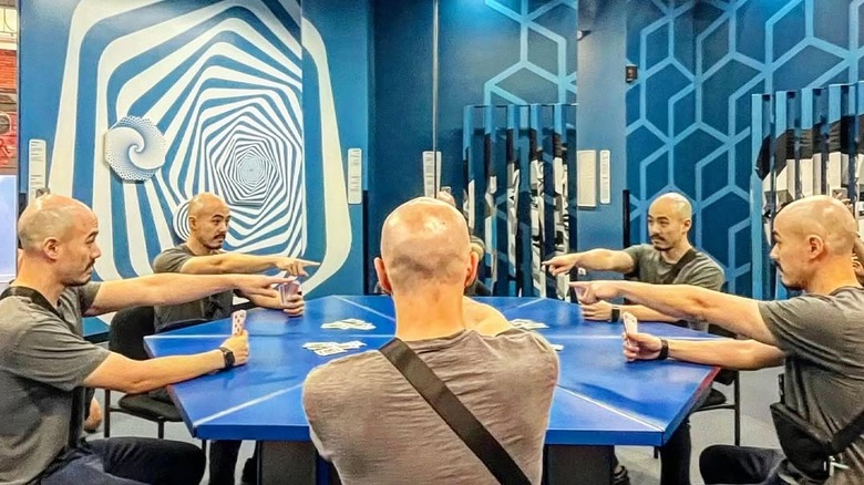 A mirror illusion, where it looks like a guest is playing cards with four clones of himself