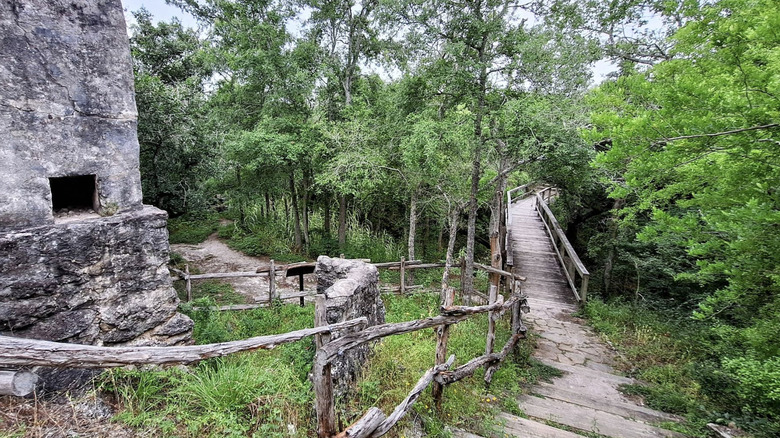 A raised walkway surrounded by stone ruins and trees at Goliad State Park and Historic Site.