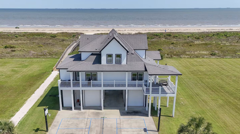 Aerial view of large white house with ocean in the background