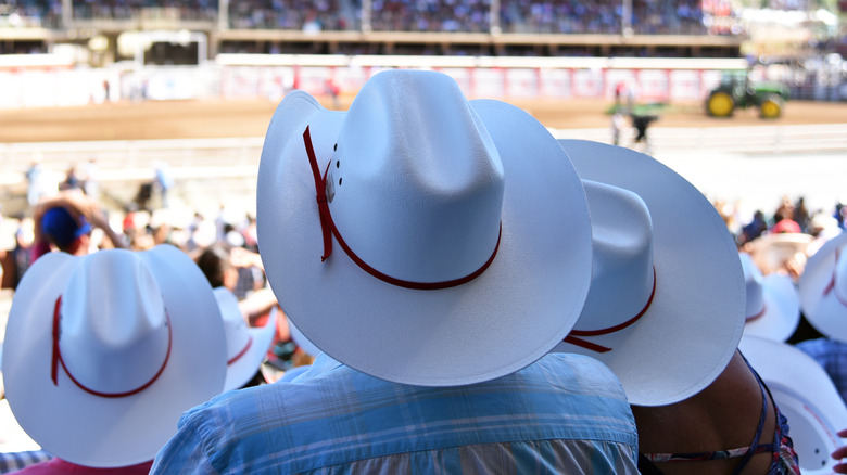 Three people wearing cowboy hats at a rodeo
