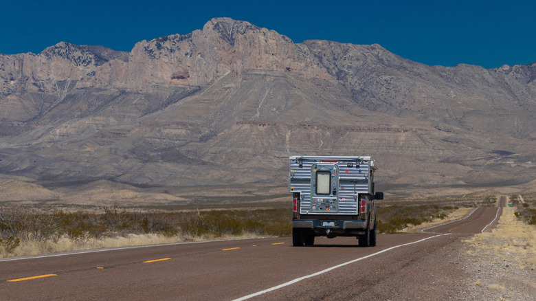 A truck camper driving toward Guadalupe Mountains National Park in northwest Texas