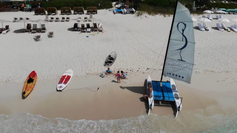 Family on the beach with sailboat and kayaks at The Somerset resort