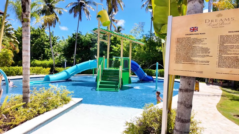 A child enjoying a shallow pool with water slides at a resort