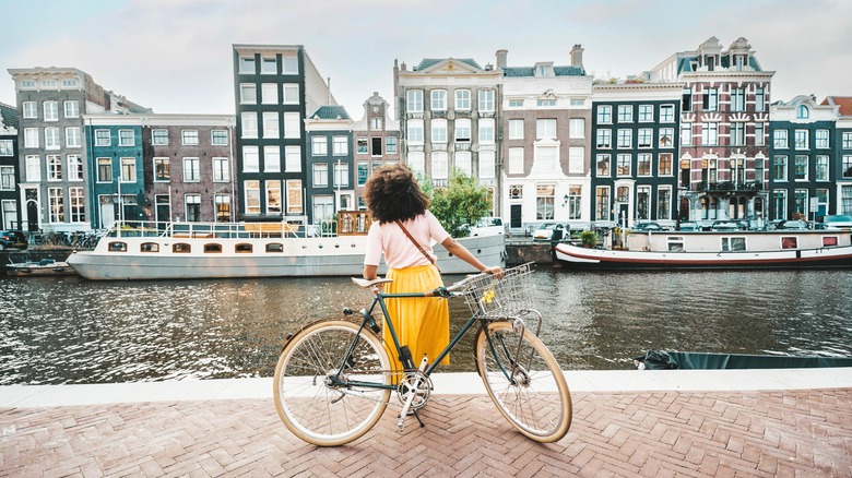 Woman in yellow skirt stands near a bike in Amsterdam