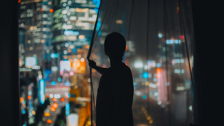 Woman gazes out at Tokyo from hotel room