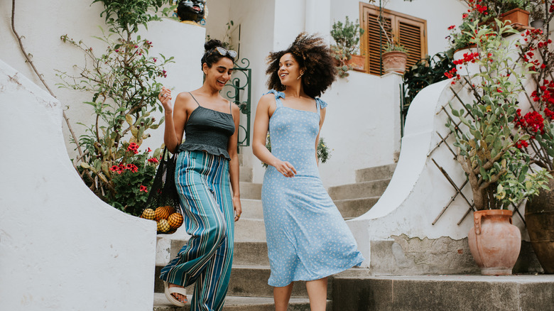 Two woman walk down steps of whitewashed home