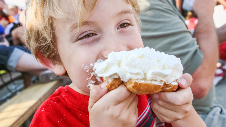 A young boy eats a giant cream puff at the Wisconsin State Fair