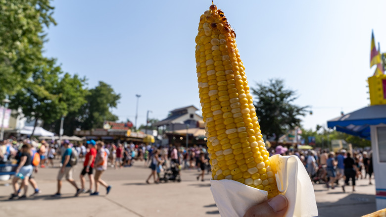 A roasted corn cob held up in front of a crowd at the Minnesota State Fair, St. Paul
