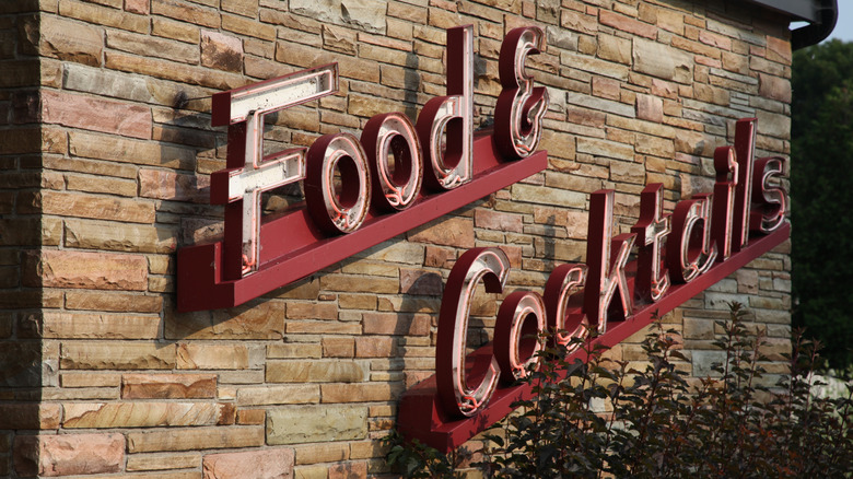A vintage neon sign on the side of a building that reads "Food & Cocktails"