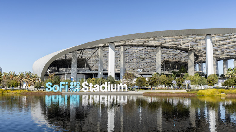 View of SoFi Stadium's lakefront with the stadium and blue and white name signage in the background