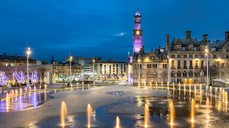 Dramatic night shot of Bradford City Hall reflected in the mirror pool in the city park, located in Bradford, West Yorkshire, UK