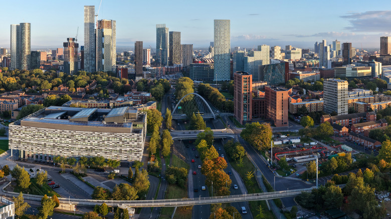 Aerial sunrise panorama of Manchester skyline featuring Princess Road Footbridge and Deansgate Square, United Kingdom