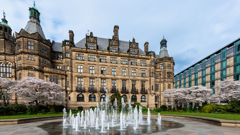 A scenic view of Sheffield city centre featuring an ornate historic town hall building alongside a contemporary urban landscape, with a decorative water fountain in the foreground