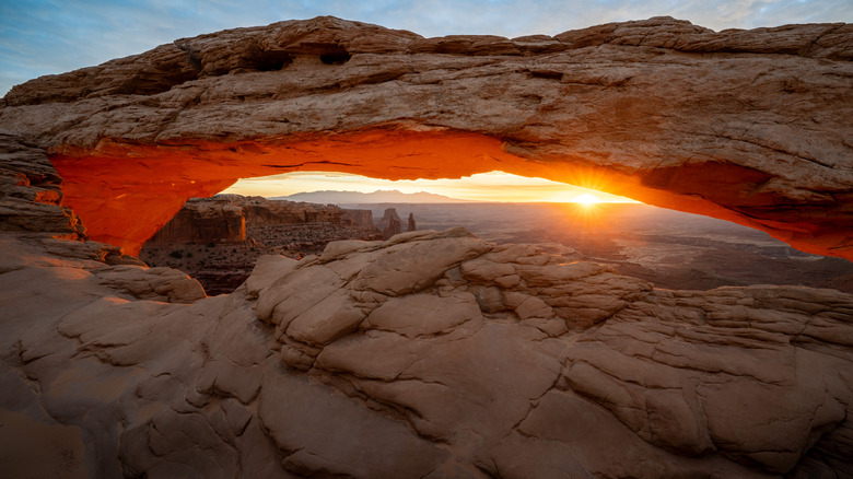 Golden sunlight pierces through the iconic Mesa Arch in Canyonlands National Park.