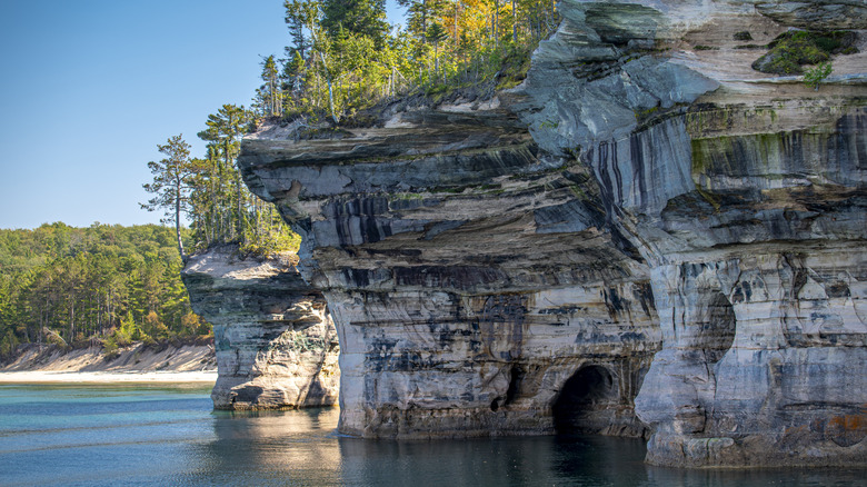 Calm blue waters of Lake Superior lap against the sandstone cliffs of Pictured Rocks National Lakeshore in Munising, Michigan