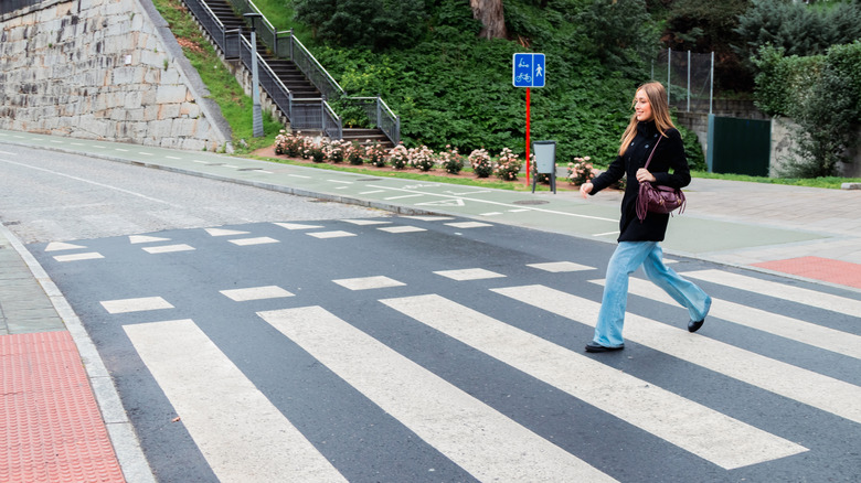 Young, smiling woman walking on a pedestrian crossing