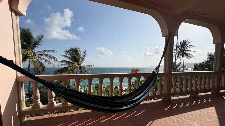 A hammock on a balcony at the Petite Anse Hotel in Grenada with the ocean in the background