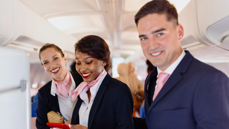Group of flight attendants smiling inside of a plane