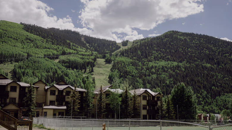 Tan condo units with green mountains in the background