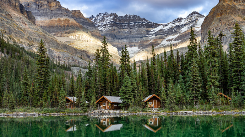 Three log cabins on the shores of a still mountain lake