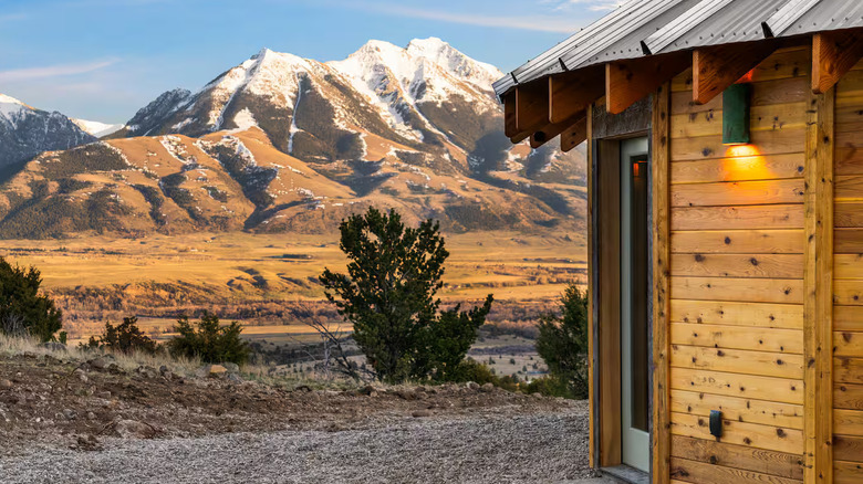 Front door of the wooden yurt with snow-capped mountains in the background