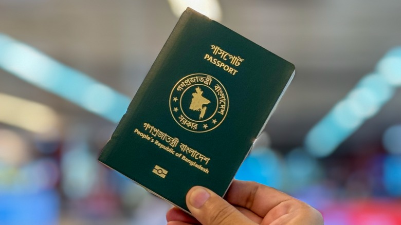 A hand holding a green Bangladeshi passport