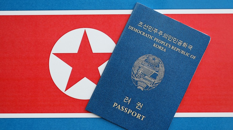 A North Korean passport with the North Korean flag behind it