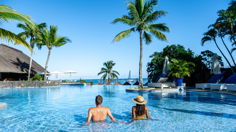 A couple sitting in an infinity pool with ocean views at a luxury resort