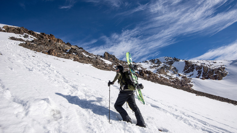 A skimo athete with his skis strapped to his back on a snowy mountain