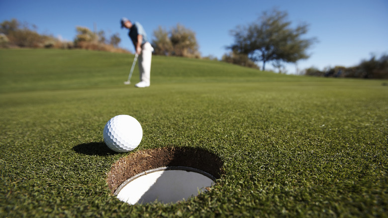 Golf ball about to fall into a hole