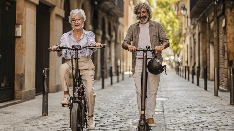 Elderly couple scootering through a European cobblestone street