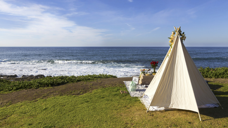A tent sits on a grassy patch beside the coast of California