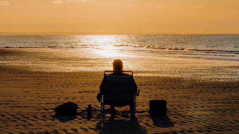 Man sitting on Mayflower Beach at sunset