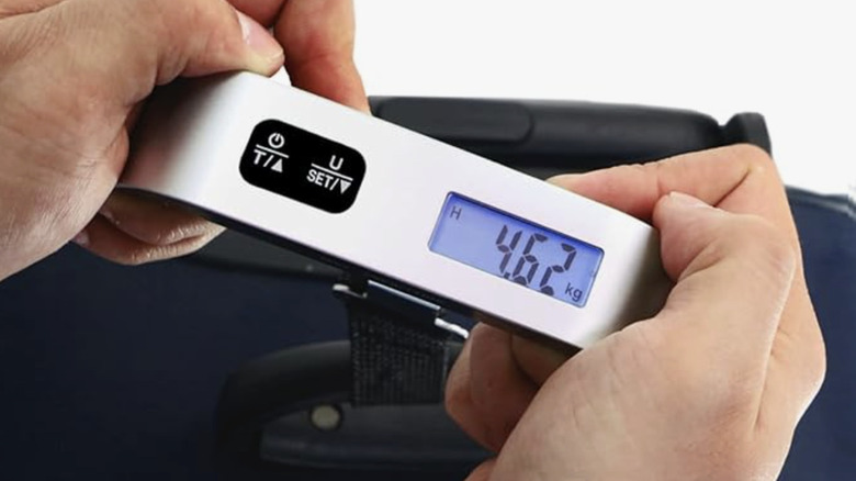 Hands holding luggage scale