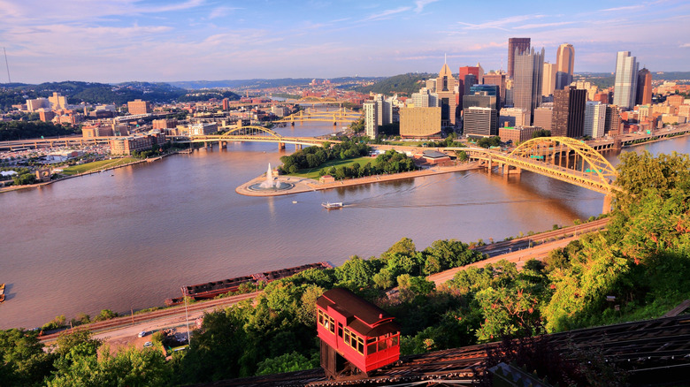 Skyline of Pittsburgh under a blue sky, with the incline in the foreground and the three rivers crossed by yellow bridges