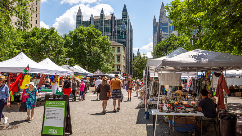 Festival in Pittsburgh's Market Square, with the PPG building in the background and white tents lining a walkway surrounded by trees under a blue sky
