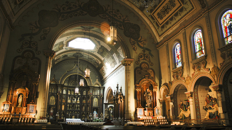 Interior of Saint Anthony Chapel, with an altar lined in reliquaries and multiple statues in alcoves under stained glass windows