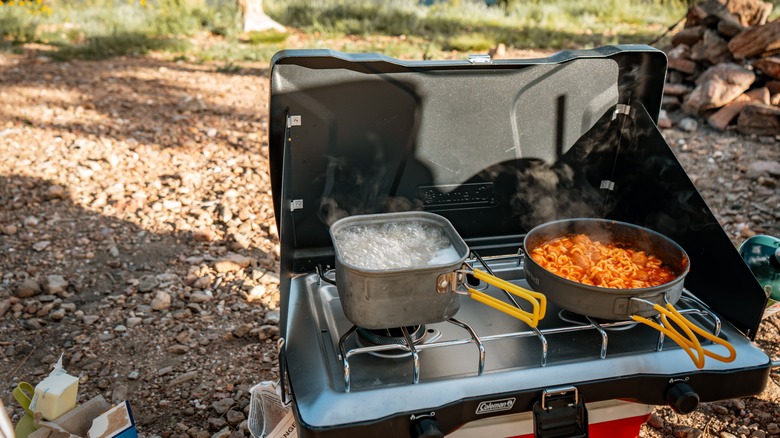 Coleman camping stove sits on cooler at outdoor site