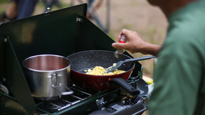 scrambled eggs being cooked on a camping stove