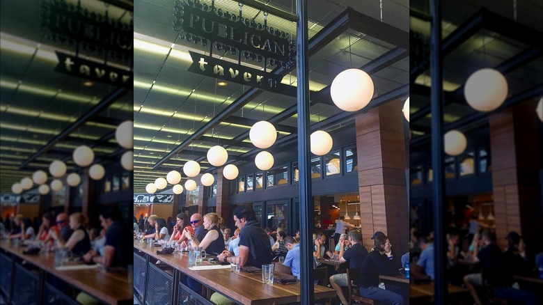 Customers sitting at a long table in Publican Tavern, O'Hare International Airport