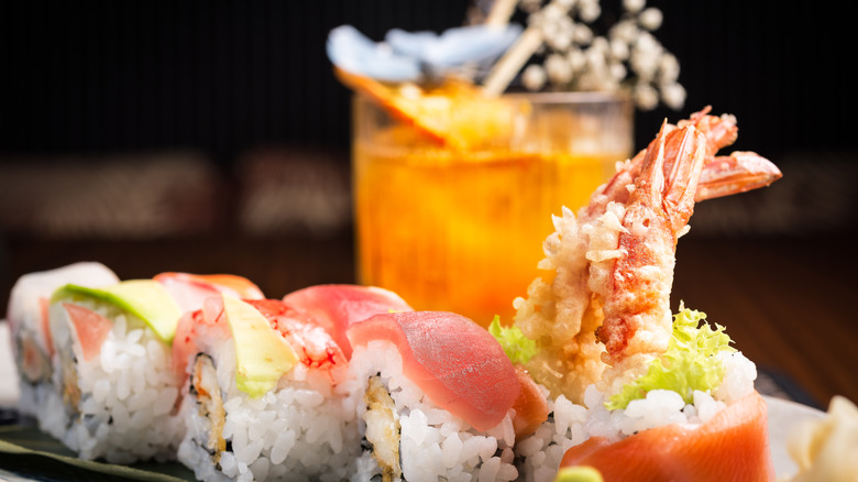 An elegant sushi roll and a cocktail in the background