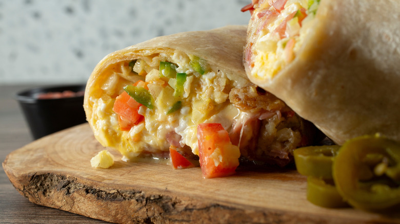 Melty breakfast burrito with eggs and vegetables in a white wrap