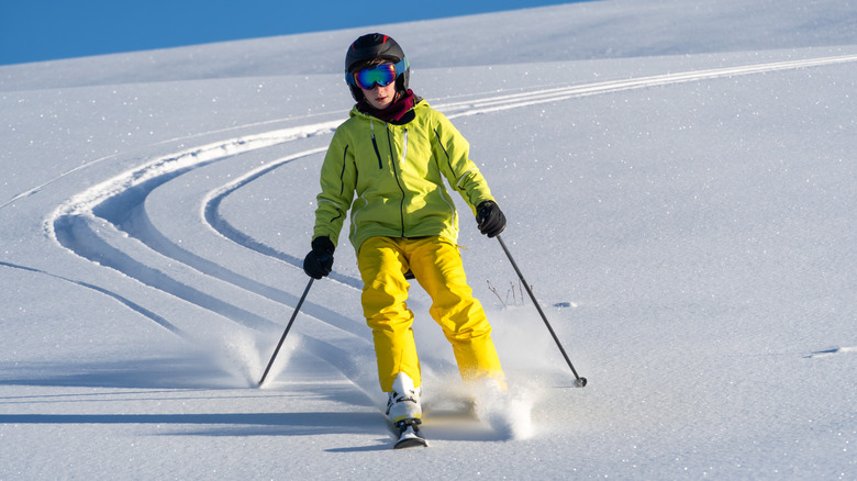Person in yellow clothing and ski gear skiing on a snowy terrain