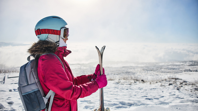 A woman skier holding skis on a snowy terrain