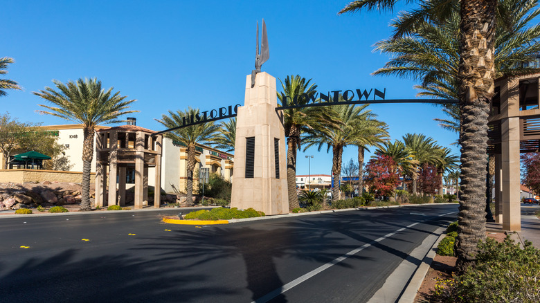 Entrance sign for Historic Downtown Boulder City with palm trees and clear blue sky