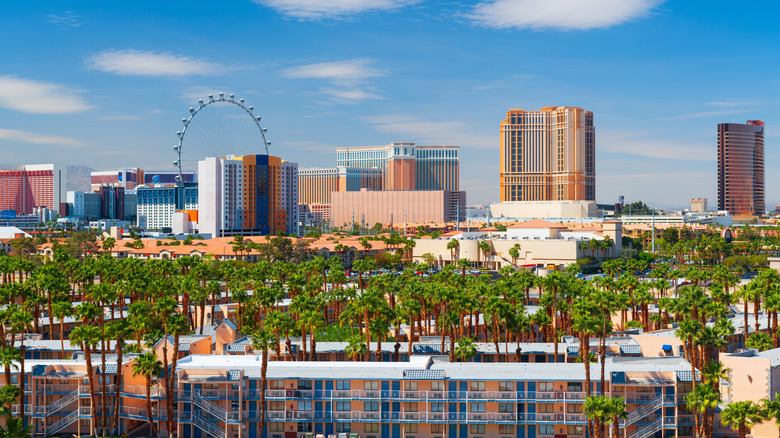 Las Vegas skyline with tall hotels, palm trees, and the High Roller observation wheel